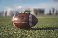 Close-up of a Wilson football on green grass in an outdoor sports setting, perfect for sports-themed visuals.